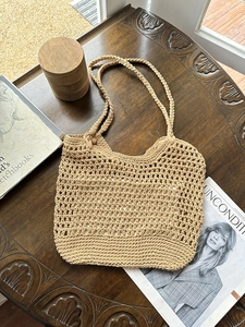 Handmade hollow crochet cotton tote bag in beige displayed on a vintage wooden table