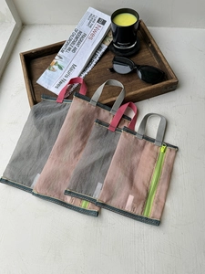 Close-up of four mesh storage bags in various sizes with handles and neon zippers