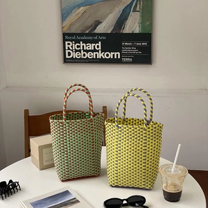 Detailed view of woven PVC beach bags in vibrant color combinations on a table