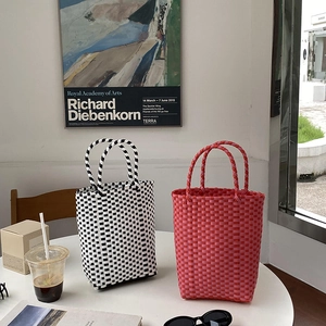 Detail of handmade PVC woven tote bag featuring checkerboard patterns and spiral handles