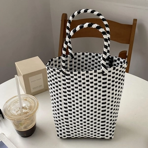 Detailed view of black and white checkered woven PVC tote bag with sturdy round handles
