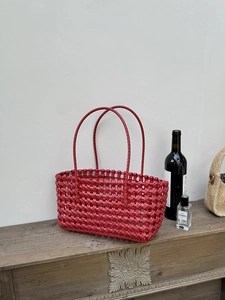 Dettaglio della borsa tote rossa intrecciata con trama a croce e sottili manici doppi