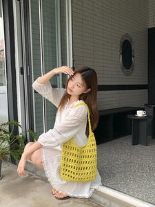 Detail of yellow hollow out woven cotton shoulder bag worn with a lace dress