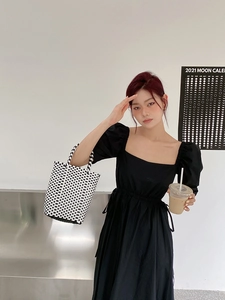 Chic black puff sleeve dress paired with a woven checkerboard pattern bucket bag detail
