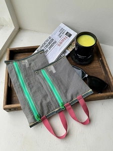 Close-up of grey mesh travel bags with vibrant neon green zippers and pink handles