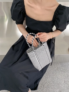 Detail of hand-woven black and white checkered PVC tote bag with sturdy round handles