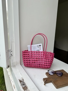 Dettaglio della borsa intrecciata fucsia con trama a griglia su base in legno