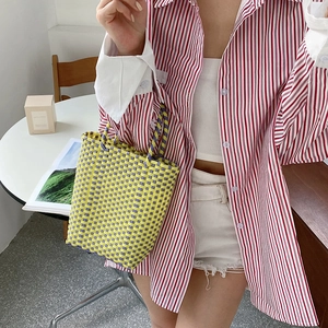 Detail of yellow and purple woven PVC tote bag styled with casual summer striped shirt