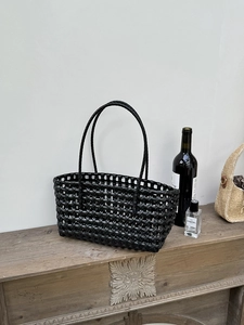 Dettaglio della borsa tote intrecciata nera con texture traforata e manici cilindrici