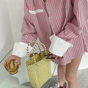 Detail of yellow and purple hand-woven PVC tote bag styled with red striped shirt