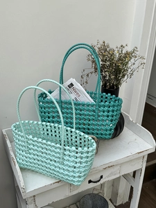 Borse a mano intrecciate a mano in turchese e verde menta su supporto in legno bianco