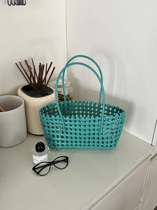 Dettaglio della borsa a cesto intrecciata blu su tavolo bianco con accessori eleganti