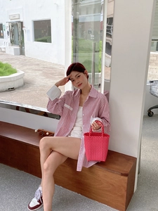 Close-up of bright pink woven PVC tote bag paired with a striped summer outfit