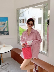 Close-up of a stylish pink PVC woven basket bag held by a model in a bright interior