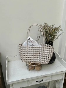 Dettaglio borsa a mano intrecciata beige su tavolo in legno vintage per vacanza