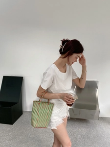 Green and orange handwoven PVC tote bag styled with a minimalist white outfit