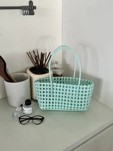 Dettaglio borsa a cesto intrecciata verde menta con design a rete e doppi manici rotondi