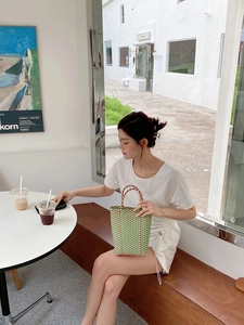 Detail of green and orange handwoven PVC tote bag with checkered pattern in cafe setting