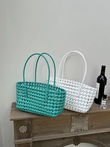 Dettaglio di borse tote intrecciate color petrolio e bianco con trama a rete traforata