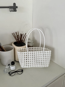 Dettaglio borsa a cesto intrecciata bianca con doppi manici in un ambiente domestico chic