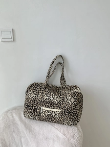 Large capacity leopard print canvas tote bag with front zipper pocket on plush white mat
