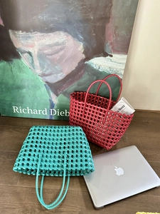 Dettaglio di borse intrecciate rosse e verde acqua con manici robusti e motivo a griglia