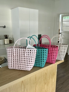 Dettaglio di borse fatte a mano intrecciate in rosa, blu, rosso e bianco crema per la spiaggia
