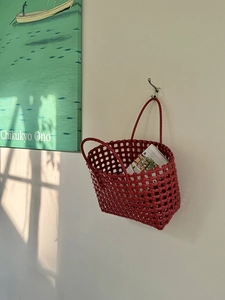 Dettaglio della borsa rossa intrecciata a mano appesa a un gancio a muro in stile moderno