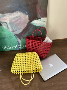 Dettaglio di borse tote intrecciate in giallo e rosso su un pavimento in legno artistico