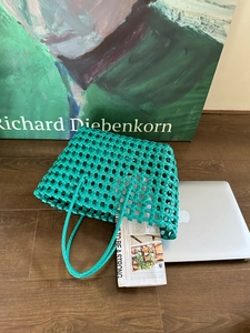 Dettaglio ravvicinato della borsa tote verde intrecciata a mano con texture in pelle intrecciata