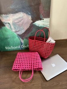 Dettaglio di borse tote intrecciate a mano rosse e viola in un ambiente di stile