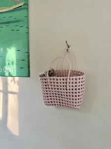 Dettaglio della borsa intrecciata rosa con struttura a griglia e doppi manici tondi
