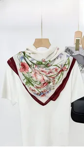 Close-up of lightweight square silk scarf with floral garden print and red borders