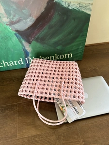 Dettaglio della borsa rosa intrecciata che mostra la trama a griglia e l'interno capiente
