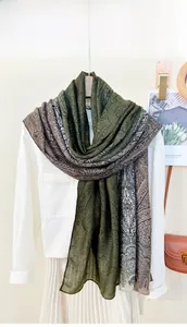 Detail of paisley print shawl in dark green and brown draped over a white shirt