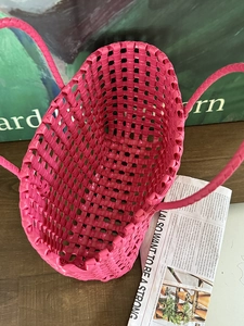 Dettaglio borsa a cesto intrecciata a mano rosa acceso con trama fitta e ampio interno