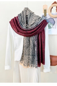 Detail of paisley print gradient scarf in burgundy and pink draped over a white outfit