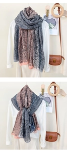 Detail view of long paisley print scarf in pink and grey worn as a stylish shawl