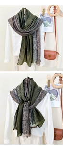 Detail of long pashmina scarf with green paisley print draped over a white outfit