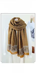 Detail of cotton and linen long scarf with chain and paisley patterns in ginger yellow