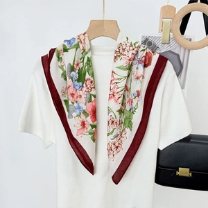 Elegant floral silk scarf with burgundy border over white shirt on a wooden hanger