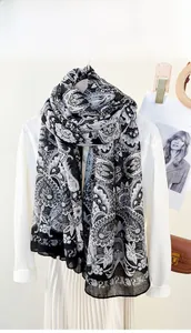 Detail of a black and white paisley print long scarf styled on a white shirt