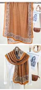 Macro detail of bohemian paisley pattern silk scarf with chain print and orange border