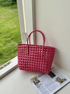 Borsa tote intrecciata a mano rosso rosa con doppi manici sul davanzale della finestra