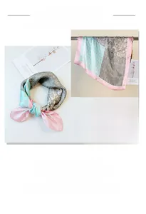 Detail of silk scarf with blue paisley pattern and pink satin borders in a flat lay view