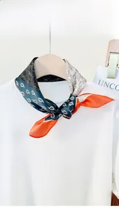 Detail of paisley silk scarf with blue and orange tones tied on a white sweater