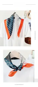 Detail view of paisley print silk scarf with orange trim and soft cashmere-feel texture