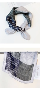 Detail of silk scarf with navy and grey paisley patterns and geometric textures