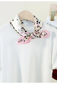 Detailed view of a floral silk scarf styled on a white T-shirt neckline as a neck accessory