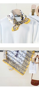 Detail of silk scarf with floral and carriage patterns worn with a white knit top